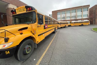 School buses line a street in front of a school