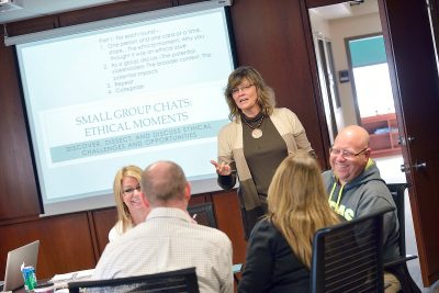 Eli Jamison stands teaching a group of adult learners.