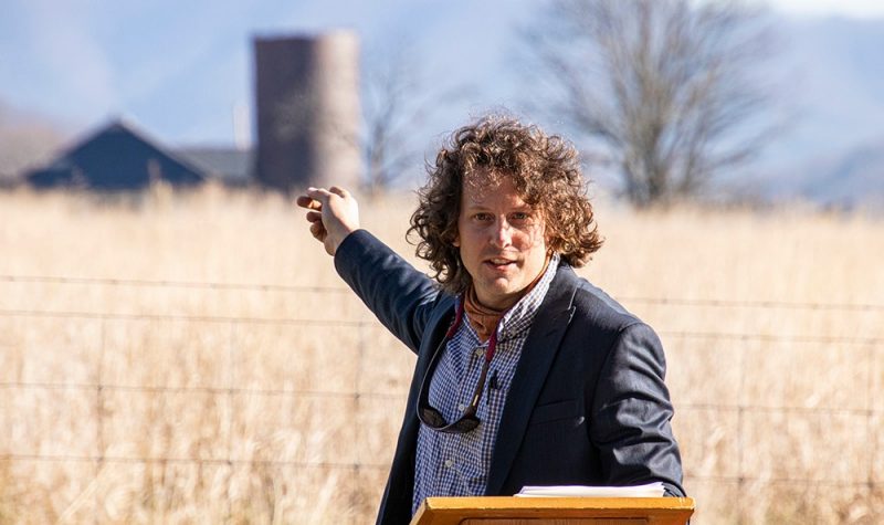 Adam Taylor points to the farm behind him
